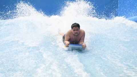 Boy play wave machine on surfboard Stock Footage 189900816