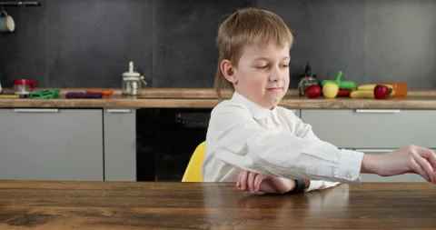 Boy with playful grimace on face pushes away bowl with chips 動画素材 314720604