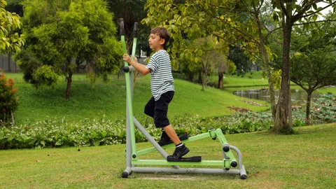 Boy playfully exercises on single ski stepper machine at park gym Stock Footage 269538097