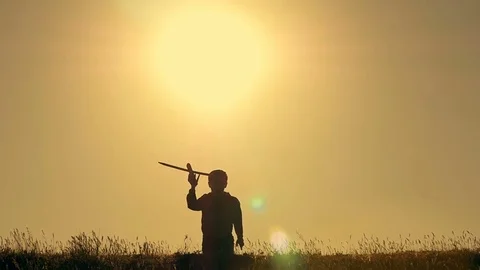 Boy playing with airplane model against orange sunset background Stock Footage 75337066