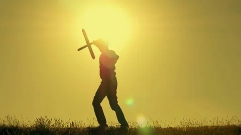 Boy playing with airplane model against orange sunset background Stock Footage 75337124