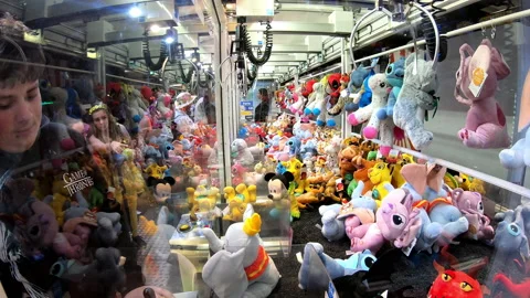 Boy playing amusement machine with hook, prize stuffed animals, 4k Stock Footage 198891947