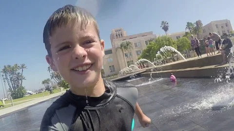 Boy Playing and Running Through City Park Fountain - GoPro POV Stock Footage 77104549