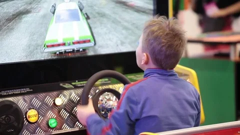 Boy playing auto simulator video arcade game Stock Footage 76877869