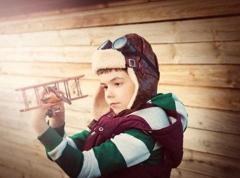 Boy playing in aviator hat with old plane Stock Photos