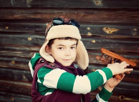 Boy playing in aviator hat with old plane Stock Photos