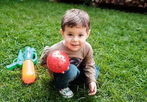 A boy playing with a ball in the backyard Stock Photos