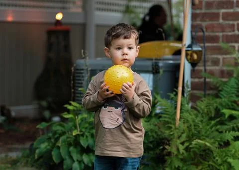 A boy playing with a ball in the backyard Stock Photos