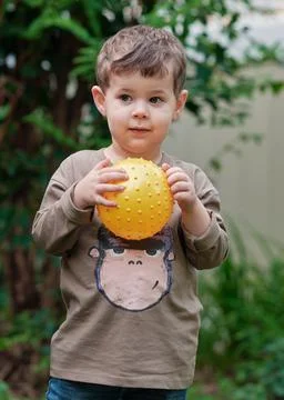 A boy playing with a ball in the backyard Stock Photos