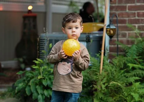 A boy playing with a ball in the backyard Stock Photos