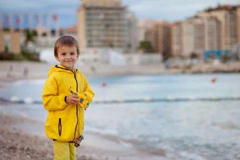 Boy, playing on the beach in the evening after rain with toys Stock Photos
