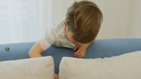 Boy playing with a blue car on the sofa Stock Footage 99999971