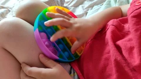 Boy playing with bright rainbow toy antistress. Flexible sensory antistress toy. Stock Footage 154716629