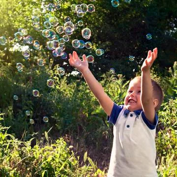 Boy playing catch soap bubbles outdoors Stock-Fotos