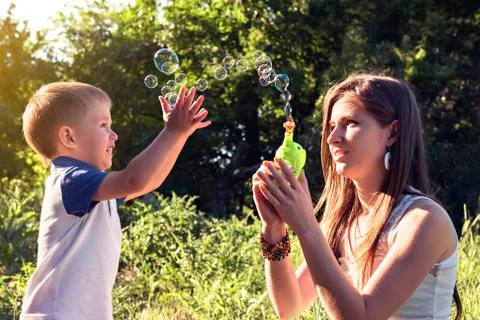 Boy playing catch soap bubbles outdoors Stock Photos