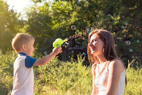 Boy playing catch soap bubbles outdoors Stock Photos