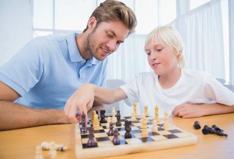 Boy playing chess with his father Stock Photos