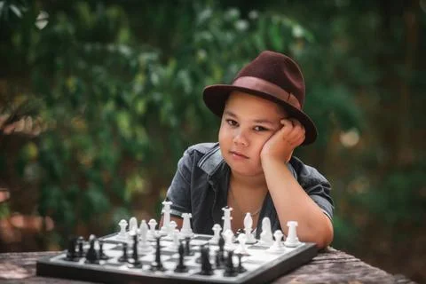 Boy playing chess looking at camera in forest Stock Photos