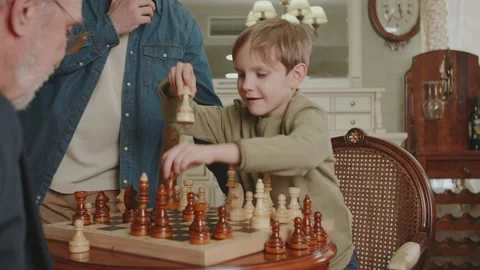 Boy is playing chess. Rearranges the piece and wins. Father is proud of his son Stock Footage 235015287