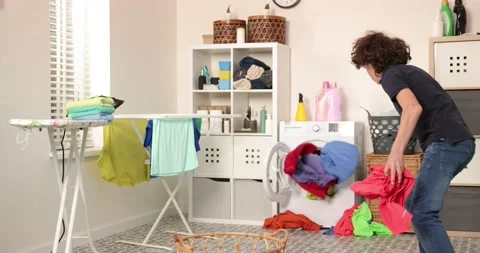 Boy is playing with clothes during laundry. Young teen boy throwing basket with Stock Footage 180150964