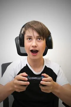 The boy is playing a computer game and sitting on a gaming chair. Stock Photos