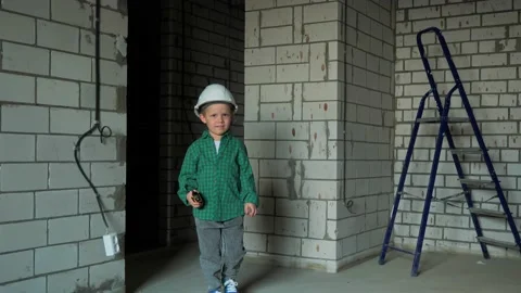 A boy is playing on a construction site with a walkie-talkie in his hands Stock Footage 238083796