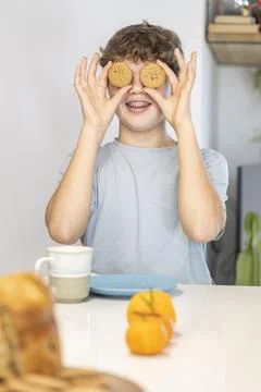 Boy playing with cookies at breakfast table 스톡 사진