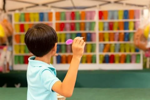 Boy playing the dart game with multicolor balloons at fair. Stock Photos
