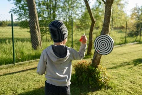 Boy playing darts at backyard Stock Photos
