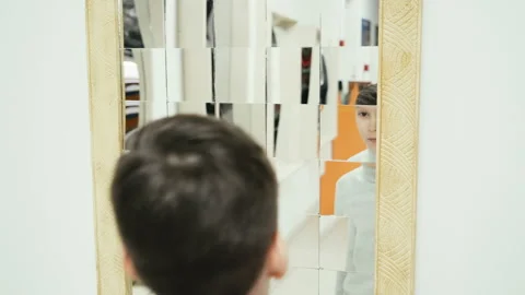 Boy playing with distorted mirror in museum of science while school excursion Stock Footage 87556837
