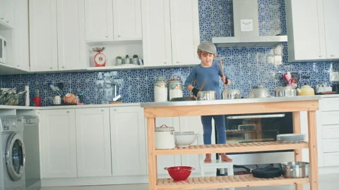 Boy playing drums in the kitchen using sticks Stock Footage 279244197