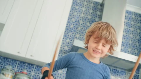 Boy playing drums in the kitchen using sticks and pots Stock Footage 279244457