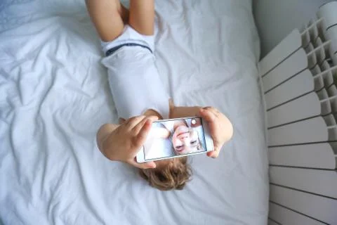 Boy playing on electronic gadget tablet in his bedroom. Social problem of Stock Photos
