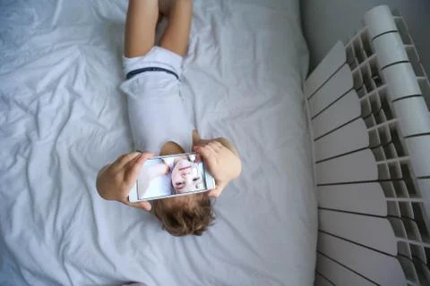 Boy playing on electronic gadget tablet in his bedroom. Social problem of Stock Photos