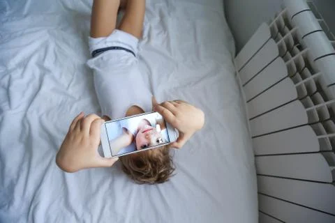 Boy playing on electronic gadget tablet in his bedroom. Social problem of Foto stock