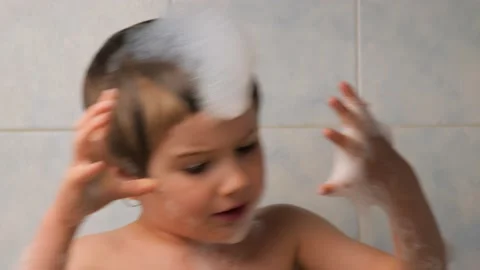 Boy playing with foam while bathing. Facial expression. A child with foam on his Stock Footage 132439404