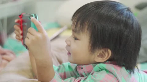 Boy Playing game on bed 스톡 동영상 192444349