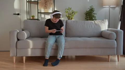 Boy Playing Games on Phone. Focused child digital entertainment indoor lifestyle Stock Footage 335478234