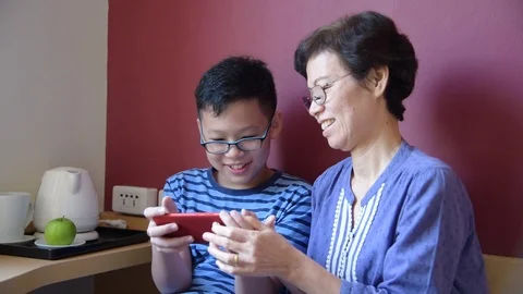 Boy playing games on smartphone with his grandma,slow motion. Stock Footage 108645804