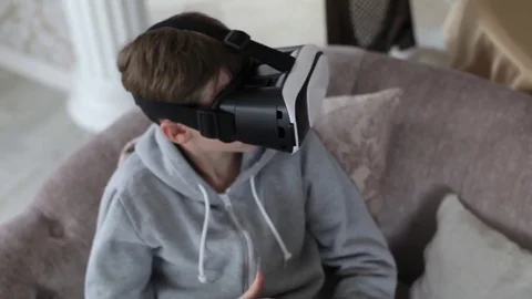 Boy Playing With Glasses Virtual Reality at Home on the Couch 스톡 동영상 74695534