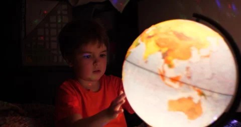 Boy Playing With Globe at Night. Child Sits on Bed in Evening Light Dreamin.. Stock Footage 303704616