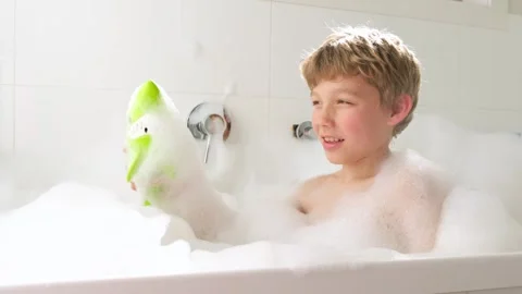 Boy playing with green shark in bubble bath Stock Footage 242831736