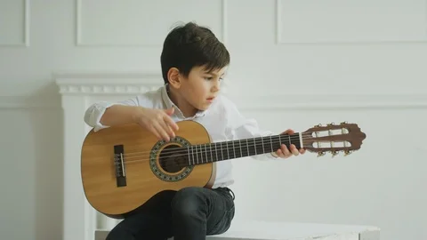 Boy playing guitar at home Stock Footage 106309093