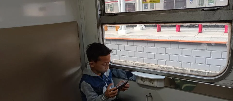 A boy is playing with his cellphone while sitting in the passenger seat Stock Photos