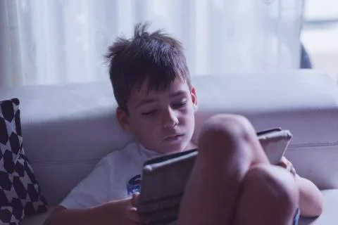 Boy playing with his tablet in the sofa Stock Photos