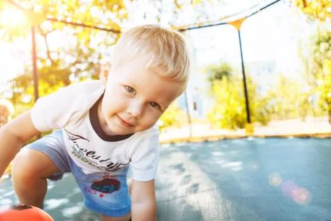 Boy playing, jumping on a trampoline, looking at camera smiling Stock Photos