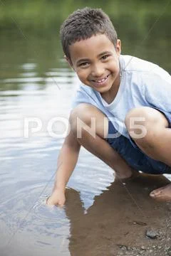 Boy playing by a lake. Stock Photos