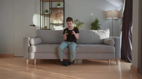 Boy Playing Mobile Game Indoors. Engrossed child smartphone digital fun relaxed Stock Footage 335477617