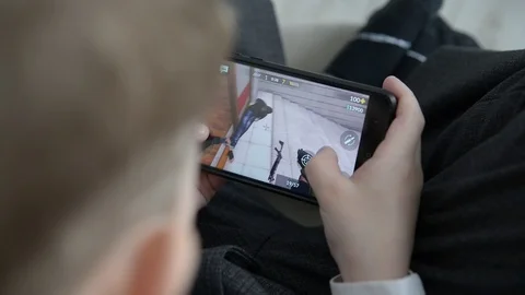 Boy playing mobile game on smartphone on sofa. Видео 127230062
