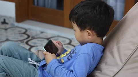 Boy playing mobile game on smartphone on ottoman. Stock Footage 158594713